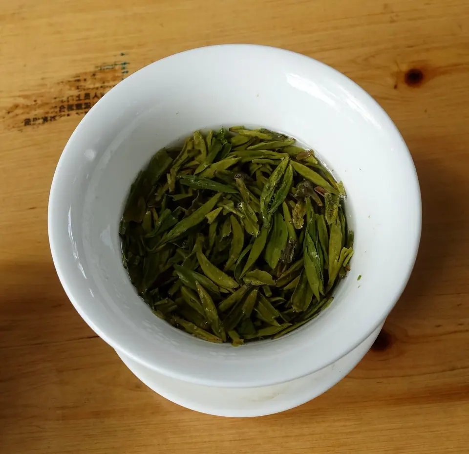 White porcelain bowl of green tea leaves on a wooden table in Chengdu’s People’s Park