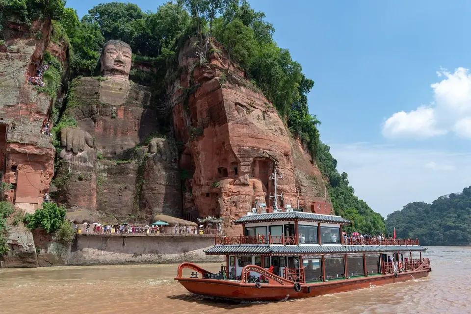 Leshan Giant Buddha carved into the riverside cliff with a sightseeing boat in the foreground