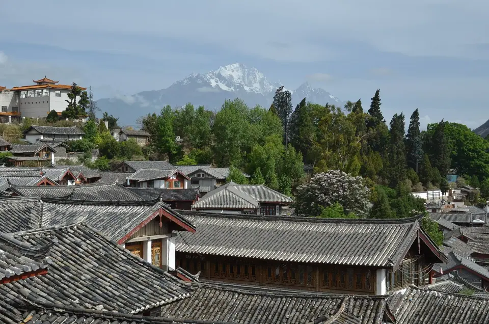 Traditional tiled rooftops and distant mountains in Lijiang’s old town