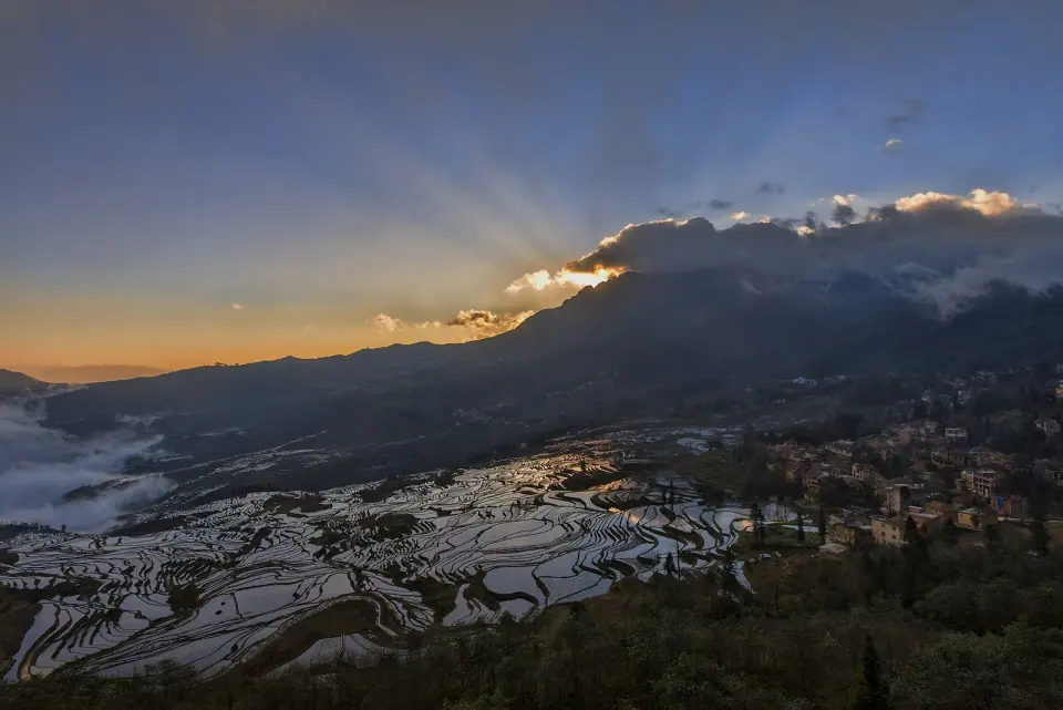 Water-filled Yuanyang rice terraces reflecting the sunrise beneath mountain ridges
